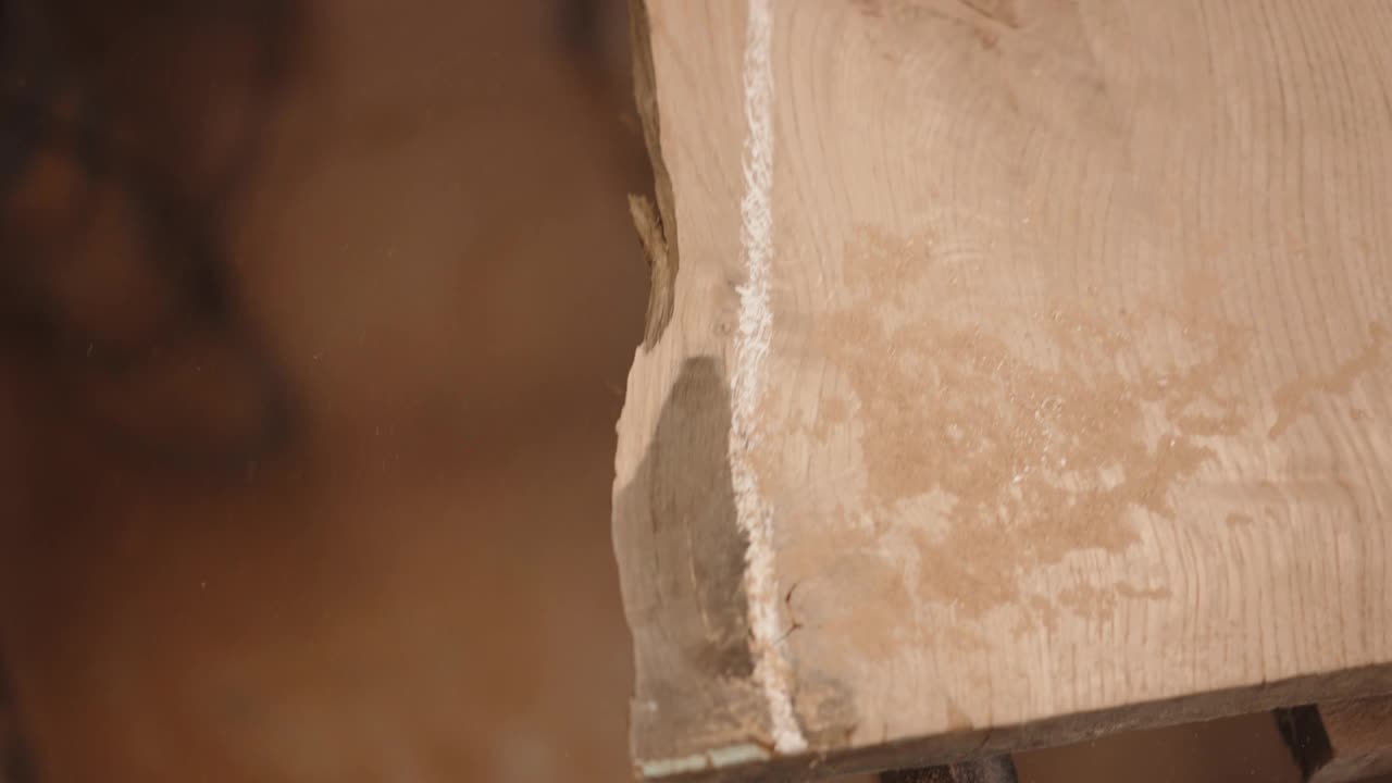 工作台上的原木板沿长度有白色标记线，以便更好地用角磨机打磨，木匠在细木工车间与木板统一工作，木制家具制造理念视频素材