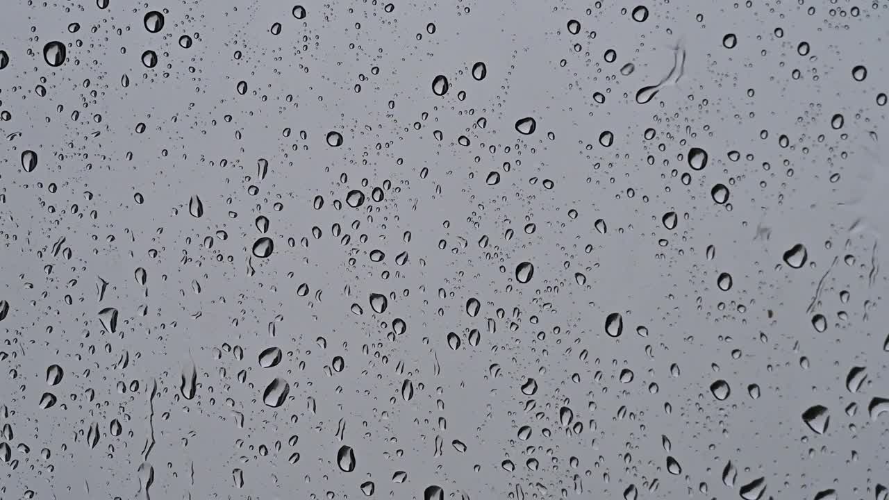 下雨时雨滴落在窗户玻璃上。视频素材