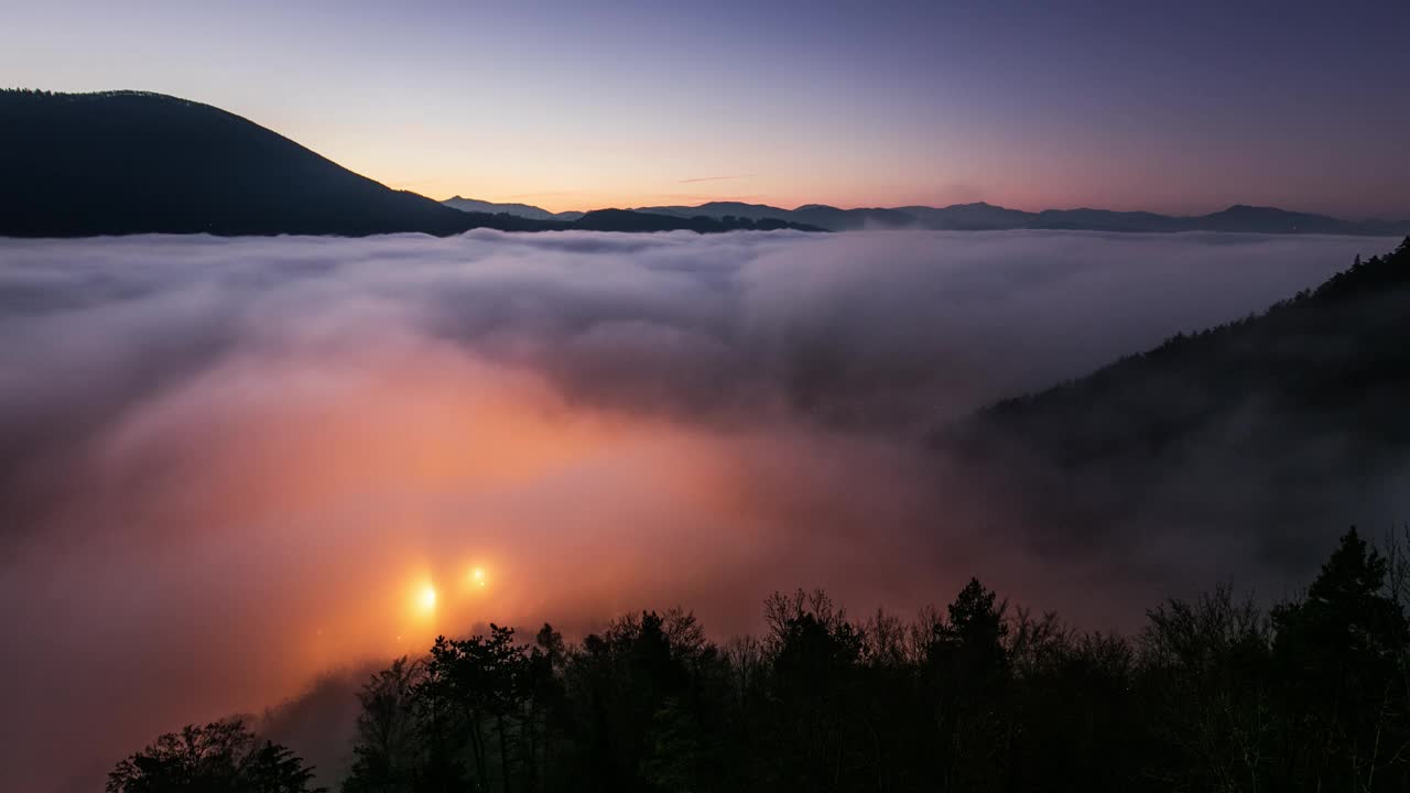 日落隐藏在云雾之后，从夜晚到日出，明亮的黄色太阳在五颜六色的云景上，蓝紫色的橙色天空。视频素材