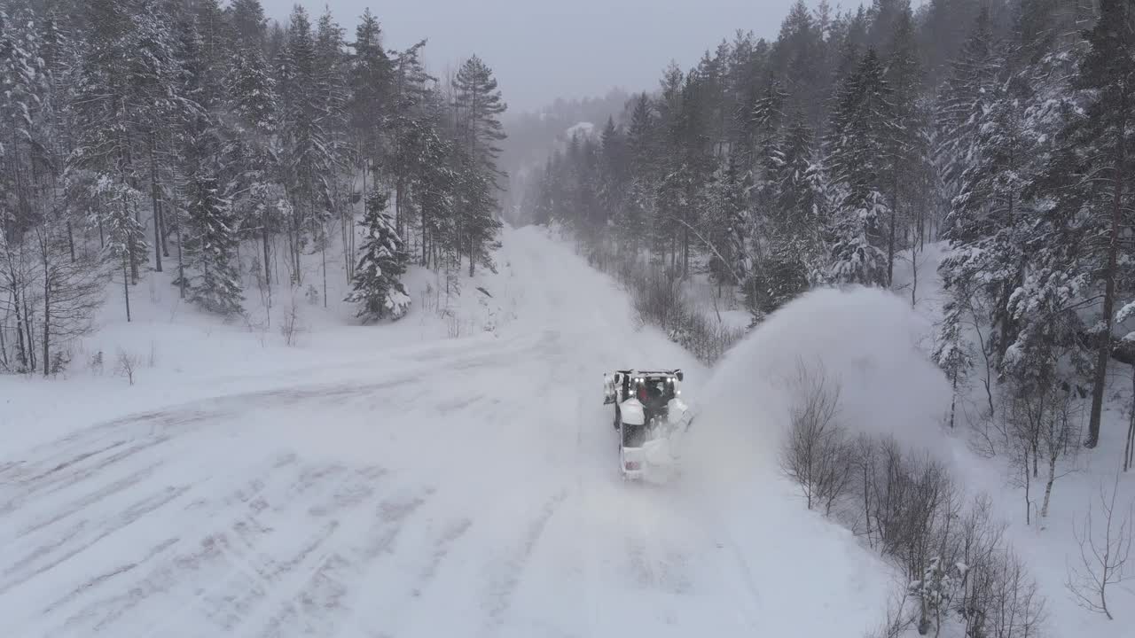 拖拉机吹雪机在冬日的乡间道路上工作。无人机航拍视频素材