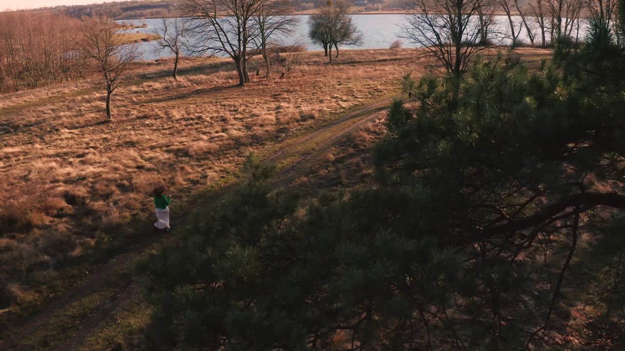 鸟瞰乌克兰河边秋天草地上穿着裙子跑步的美女视频素材