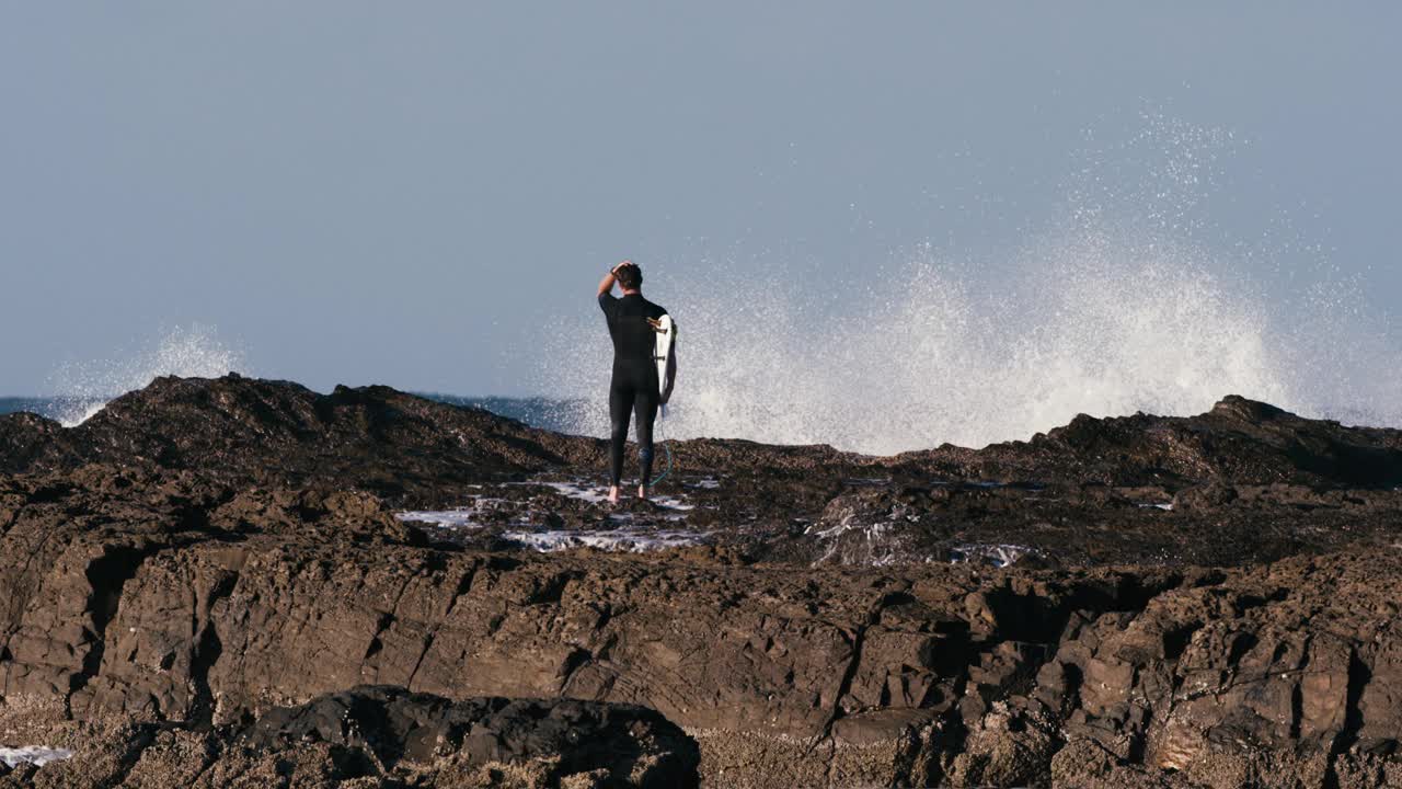 海浪冲击海岸时，冲浪者站立视频素材