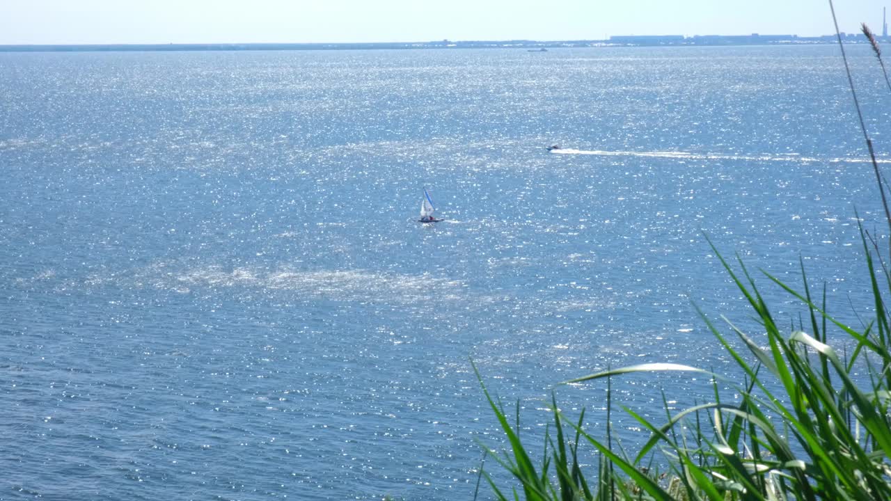 海景。在一个阳光明媚的夏日，一艘帆船独自驶过大海。航海。白帆双体船在公海上航行。赛舟会。在帆船上迎风移动的游艇之旅。视频素材