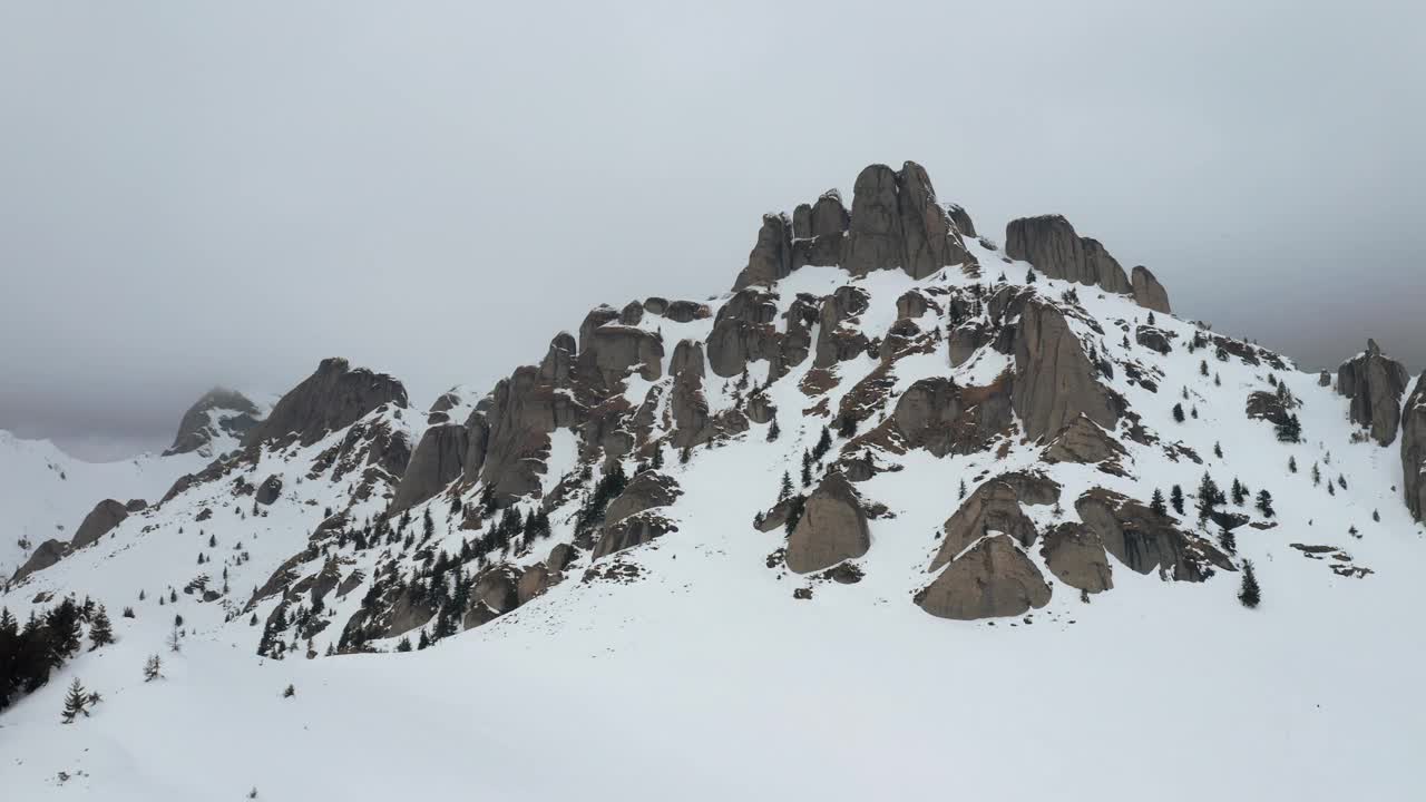 云雾缭绕，白雪覆盖的丘卡斯山脉有岩石山峰和常青树视频素材