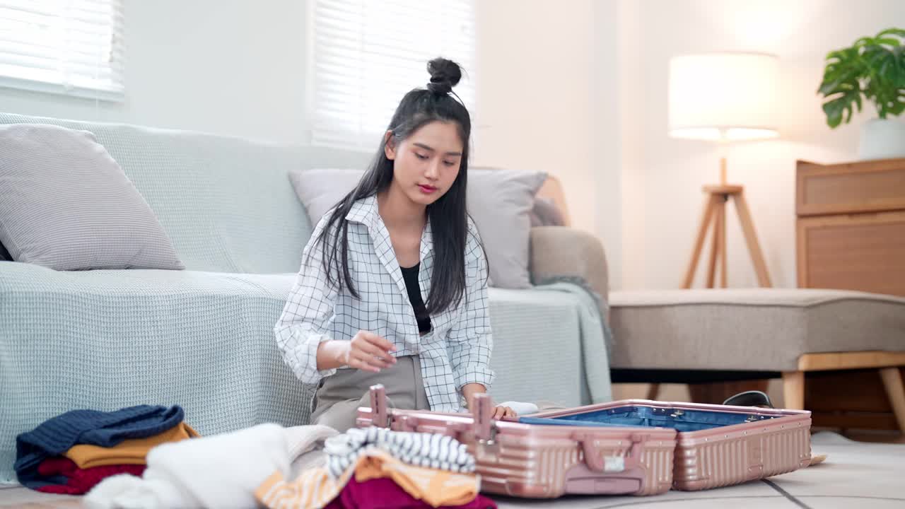 一名亚洲妇女整理她的物品，把它们装进旅行袋，准备去度假冒险视频素材