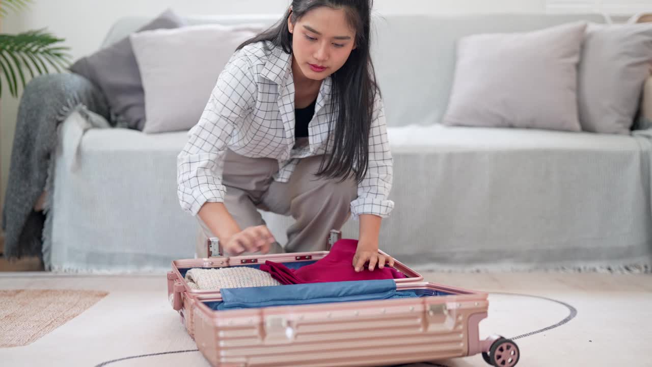 一名亚洲女子小心翼翼地把随身物品装进旅行袋，准备在一个漫长的周末进行一次冒险之旅视频素材