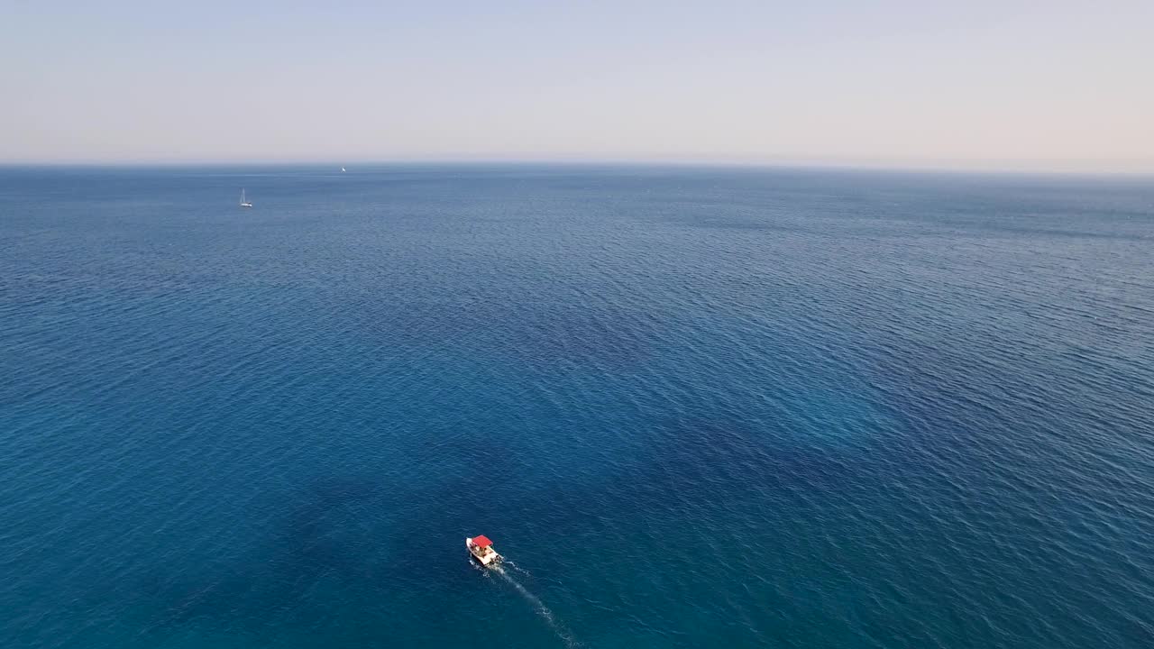 一艘小船在绿洲海滩附近的水晶水面上，扎金索斯的keri洞穴，鸟瞰图视频素材