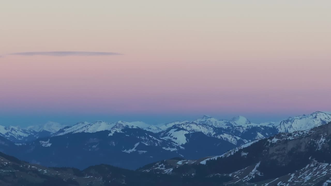 无人机镜头展示了日出的空灵之美，照亮了雪山的轮廓。视频素材