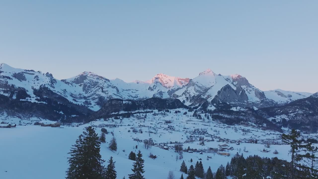 无人机拍摄的壮观的雪山轮廓，鸟瞰图捕捉日出的宁静氛围。视频素材