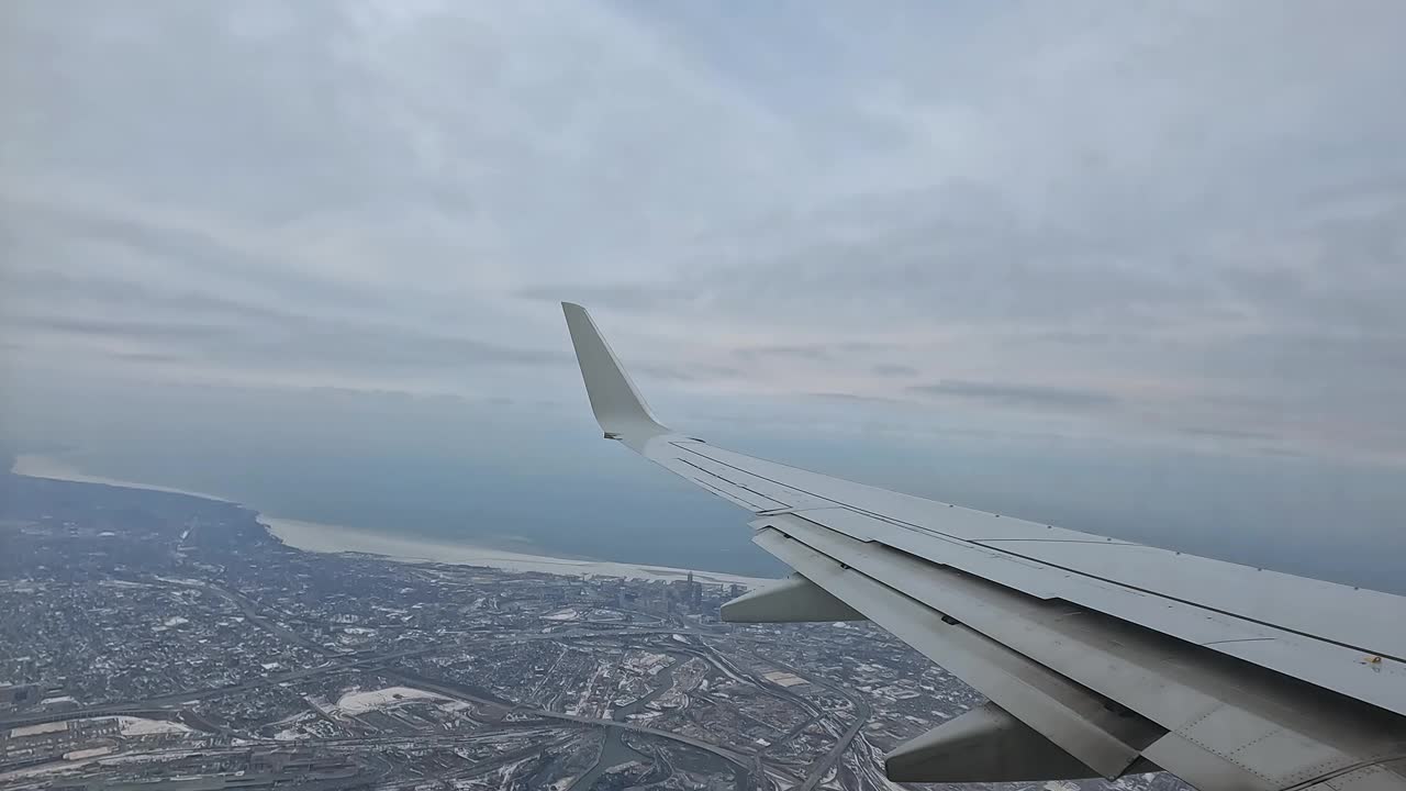 冬季从飞机机翼上鸟瞰积雪覆盖的城市景观视频素材