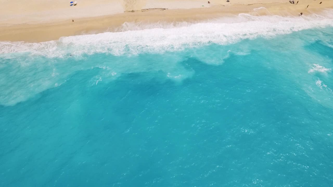 从空中俯瞰，绿松石色的海浪轻轻地拍打着希腊凯法利尼亚默托斯海滩的沙滩视频素材