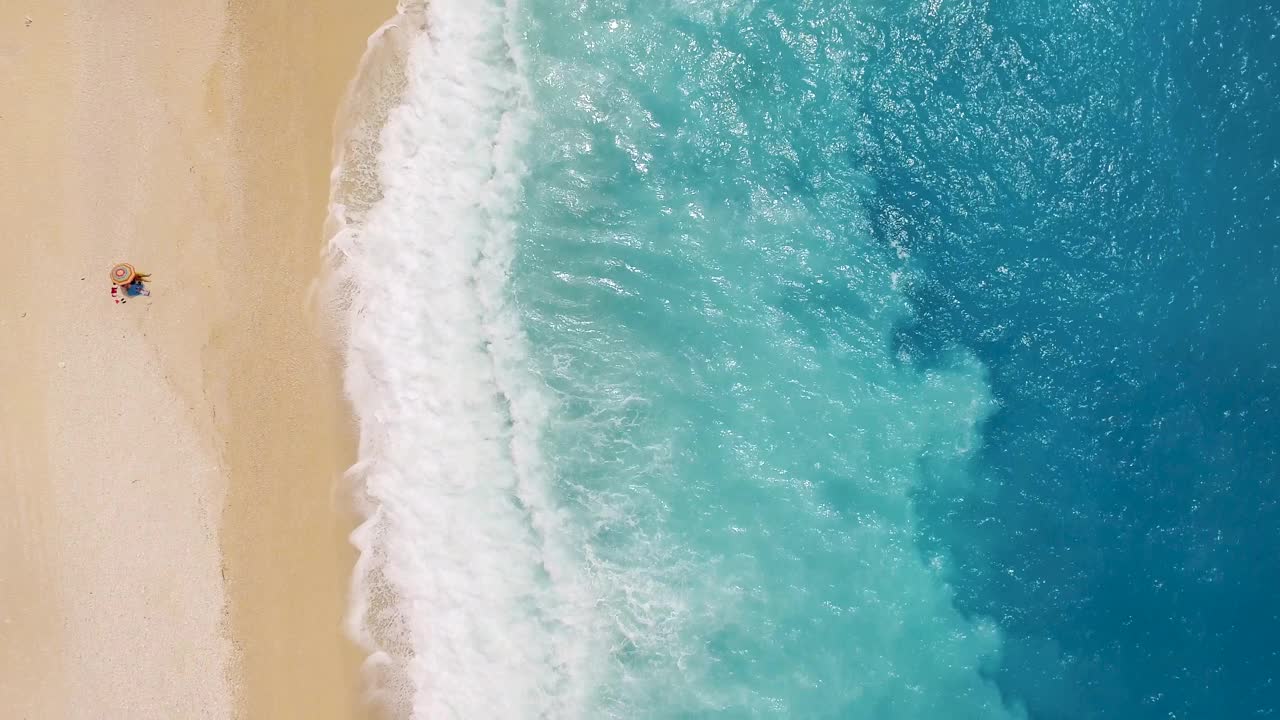 默托斯海滩上一个人躺在沙滩上，碧绿的海浪拍打着海岸，鸟瞰图视频素材