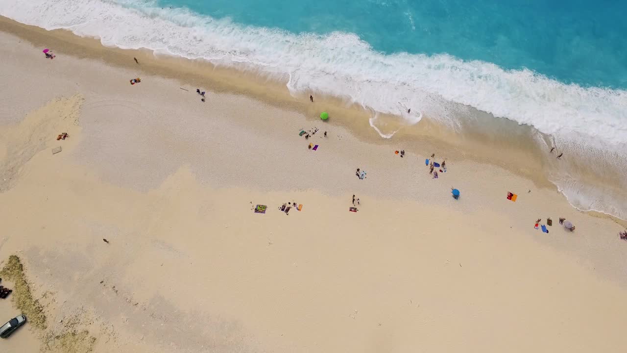 鸟瞰图，希腊凯法利尼亚的Myrtos海滩，绿松石般的海水和散落在沙滩上的日光浴者视频素材