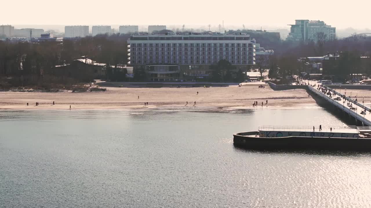 冬天的下午在Kołobrzeg码头。平静的大海，万里无云的天空。游客沿着码头散步。视频素材