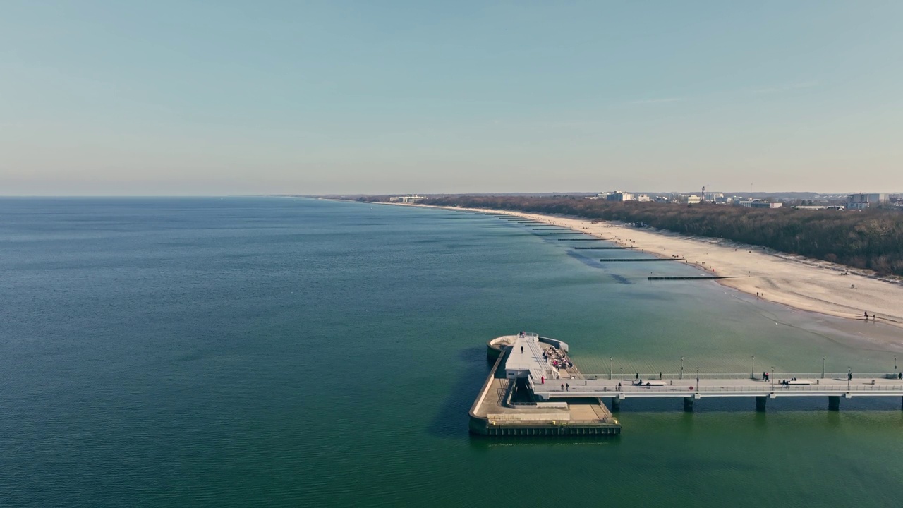 冬天的下午在Kołobrzeg码头。平静的大海，万里无云的天空。游客沿着码头散步。视频素材