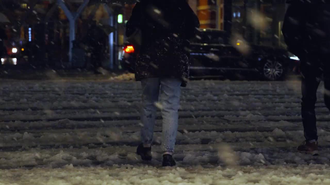 在东京丸之内站的十字路口，夜间的东京下着雪，行人走在积雪的道路上视频下载