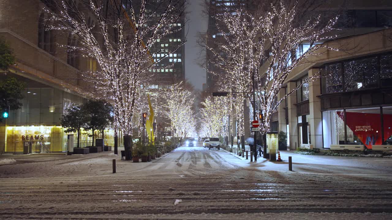 东京的夜雪，街树的灯光，丸之内的雪路上过往的汽车视频下载