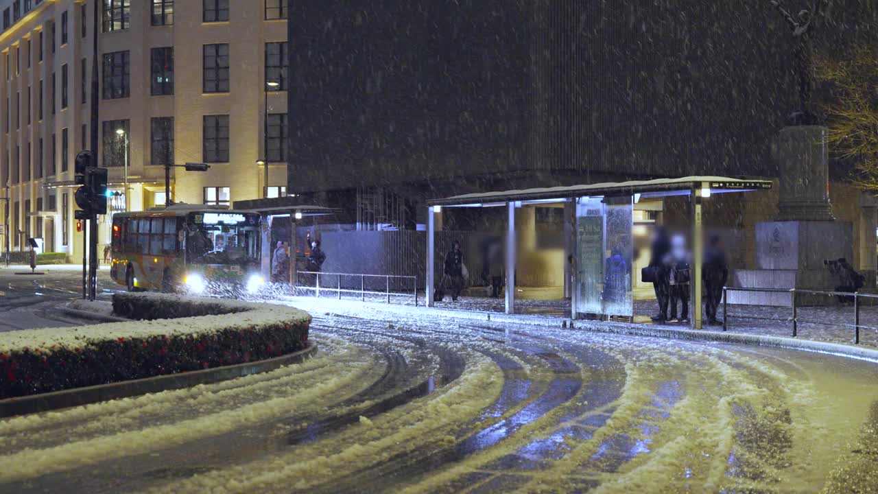 图为，东京晚上下着雪，人们在东京站的公共汽车站排队等候视频素材