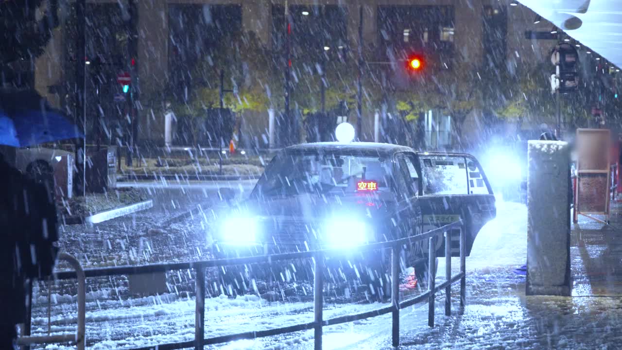 图为，东京夜间下着雪，人们在东京站的出租车站登上出租车视频素材