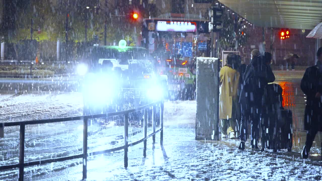 图为，东京夜间下着雪，人们在东京站的出租车站登上出租车视频下载