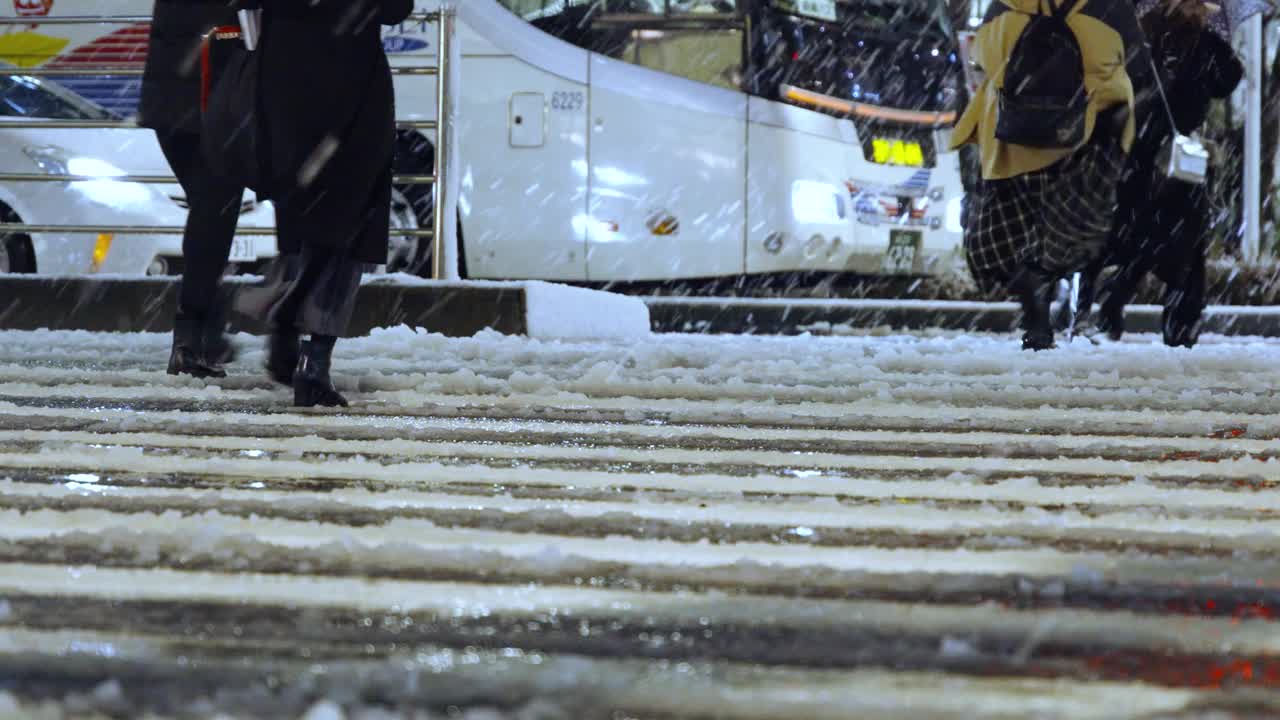 在东京车站的十字路口，夜间的东京下着雪，行人走在积雪的道路上视频素材