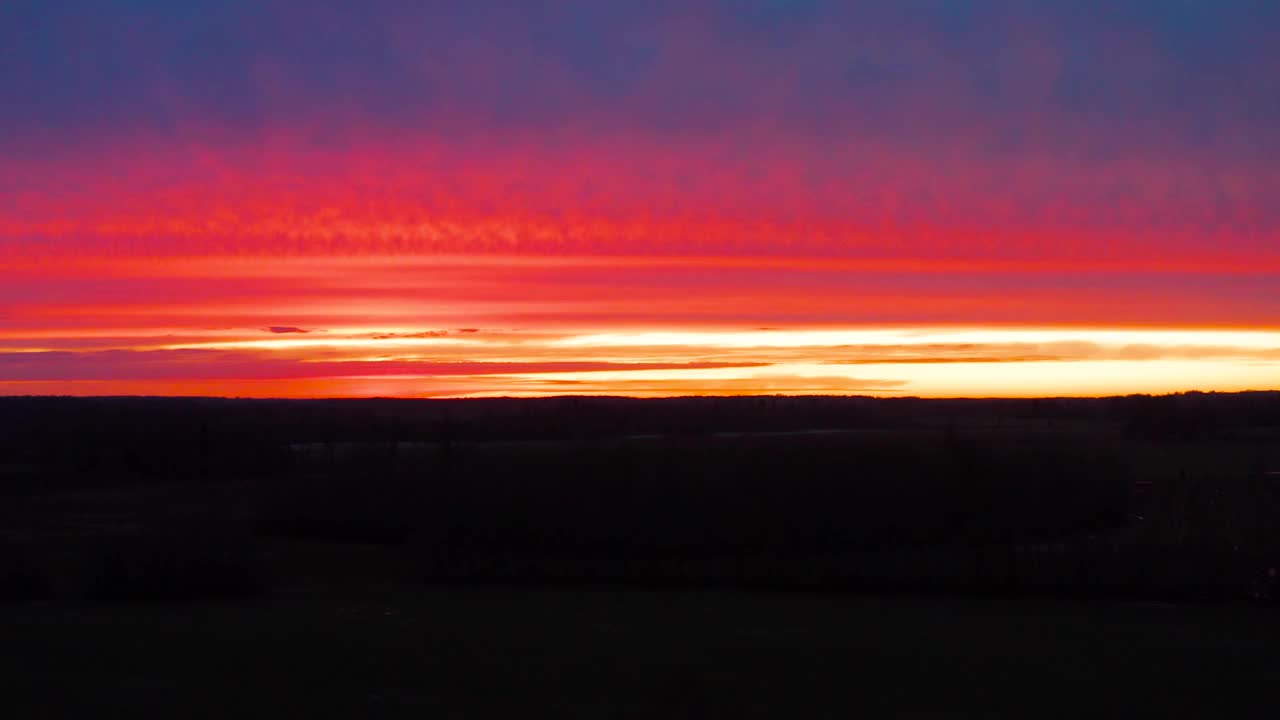 鸟瞰图在黑暗的土地，而多彩的黄金小时夕阳照亮天空视频素材