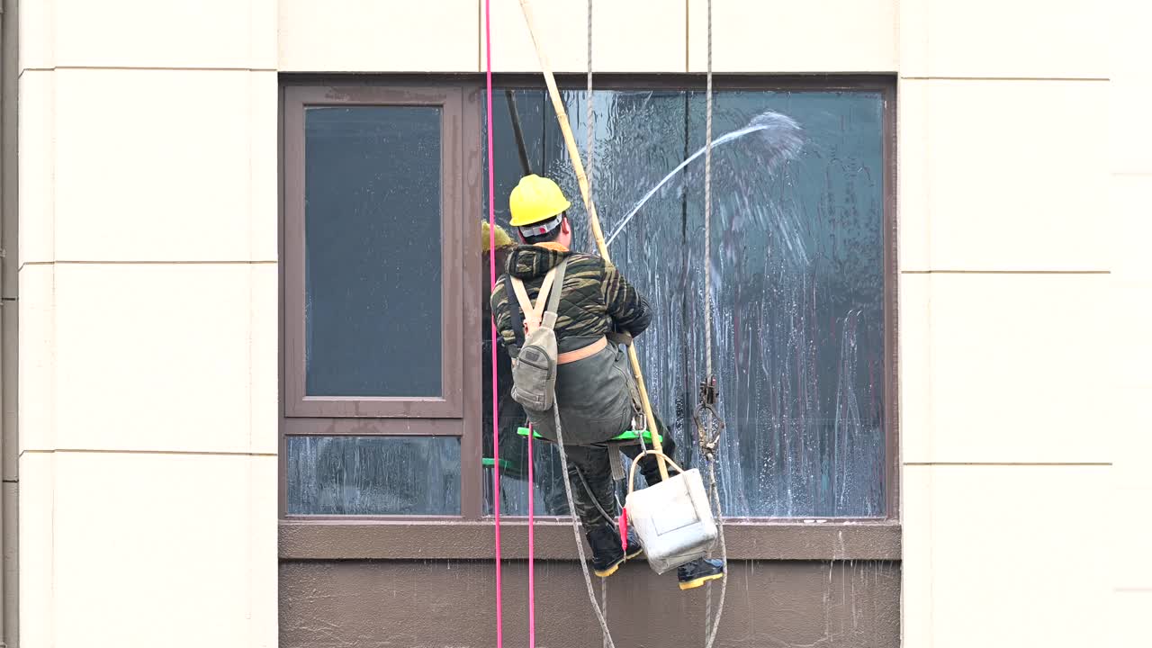 工人们在高层建筑外清洗玻璃视频下载