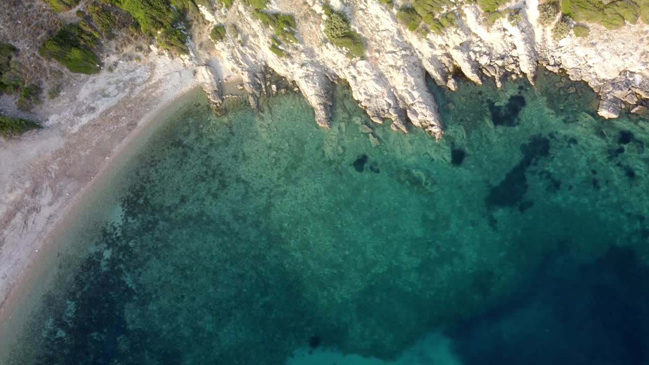 鸟瞰图，岩石海岸和树木环绕着清澈碧蓝的湖水视频素材