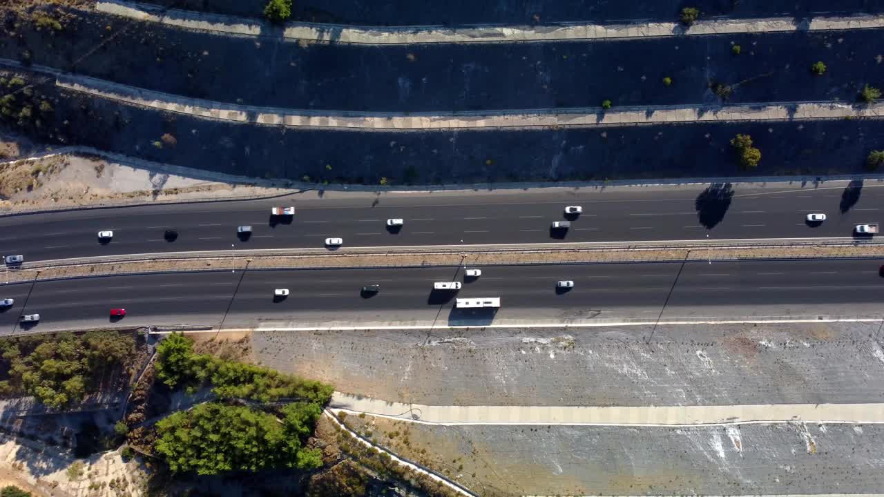 鸟瞰图，汽车行驶在两旁是建筑物和树木的沥青公路上视频素材