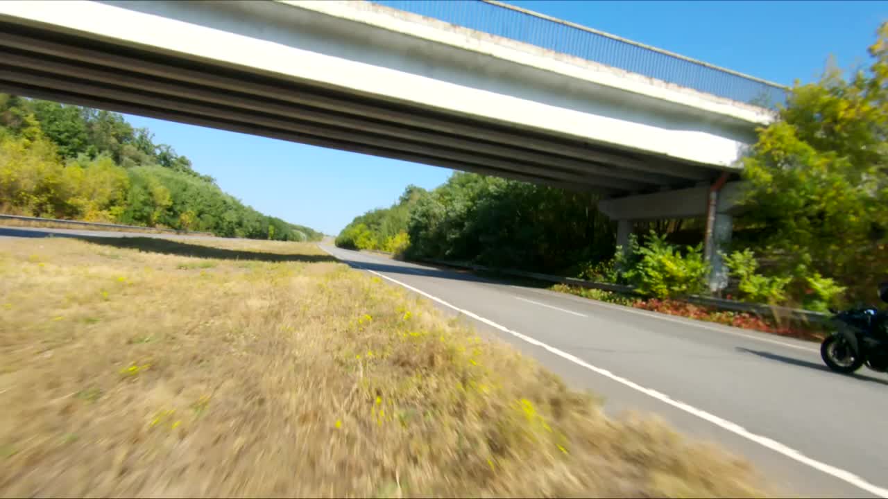 空中拍摄的男子骑着现代运动摩托车在高速公路上在夏天的一天。摩托车手在乡间公路上驾驶摩托车。有人在旅途中骑自行车。自由和冒险的概念视频素材