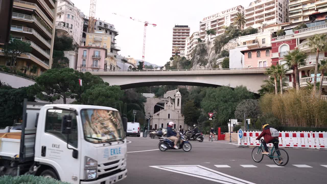 一辆白色的自卸卡车驶过城市街道，经过建筑物和树木视频下载