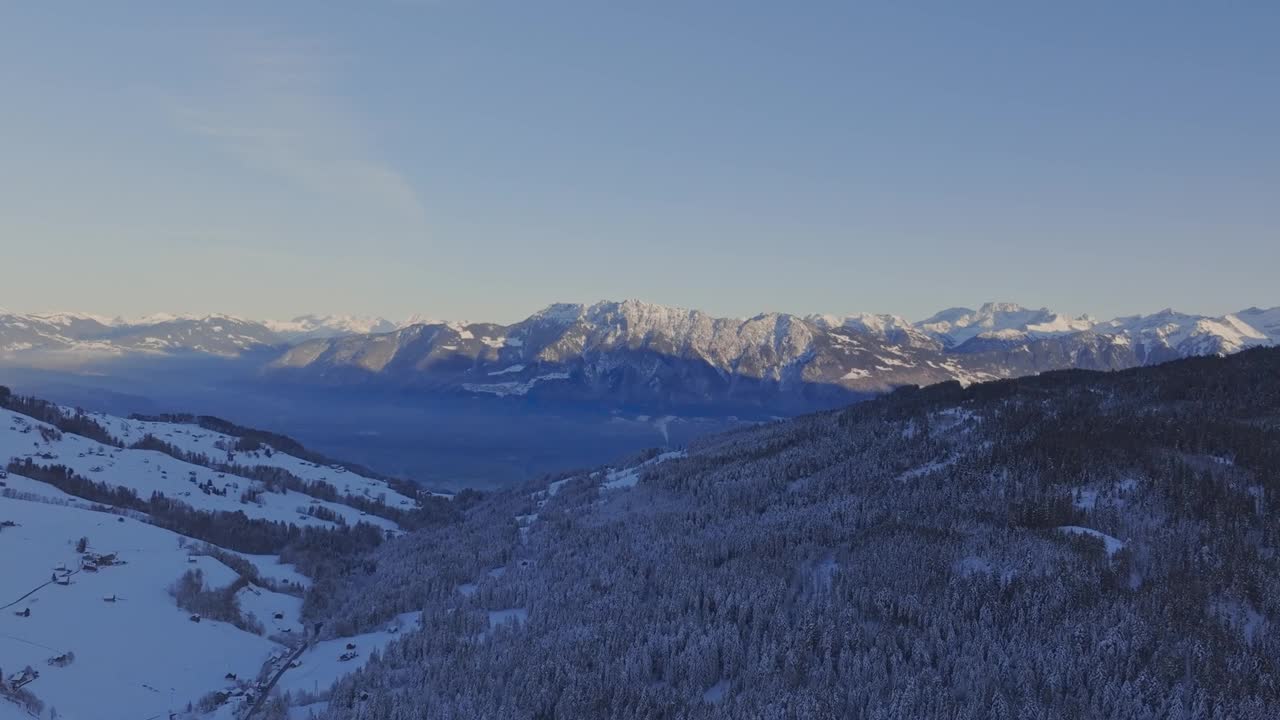 无人机拍摄的黎明天空在雪山上投射出剪影。视频素材