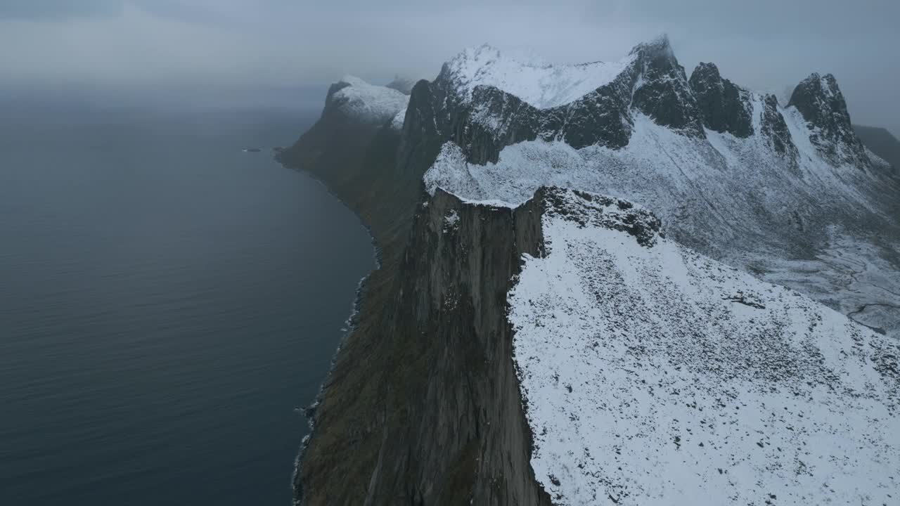 挪威森加岛上白雪覆盖的赫斯滕山，阴天下俯瞰大海的悬崖视频素材