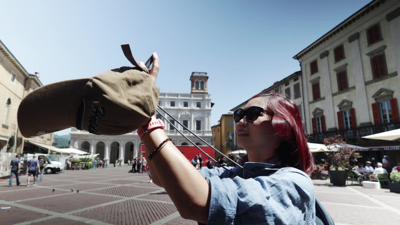 快乐的年轻亚洲女游客用手机自拍，女游客在意大利度假旅行时拍照，录制视频。视频素材