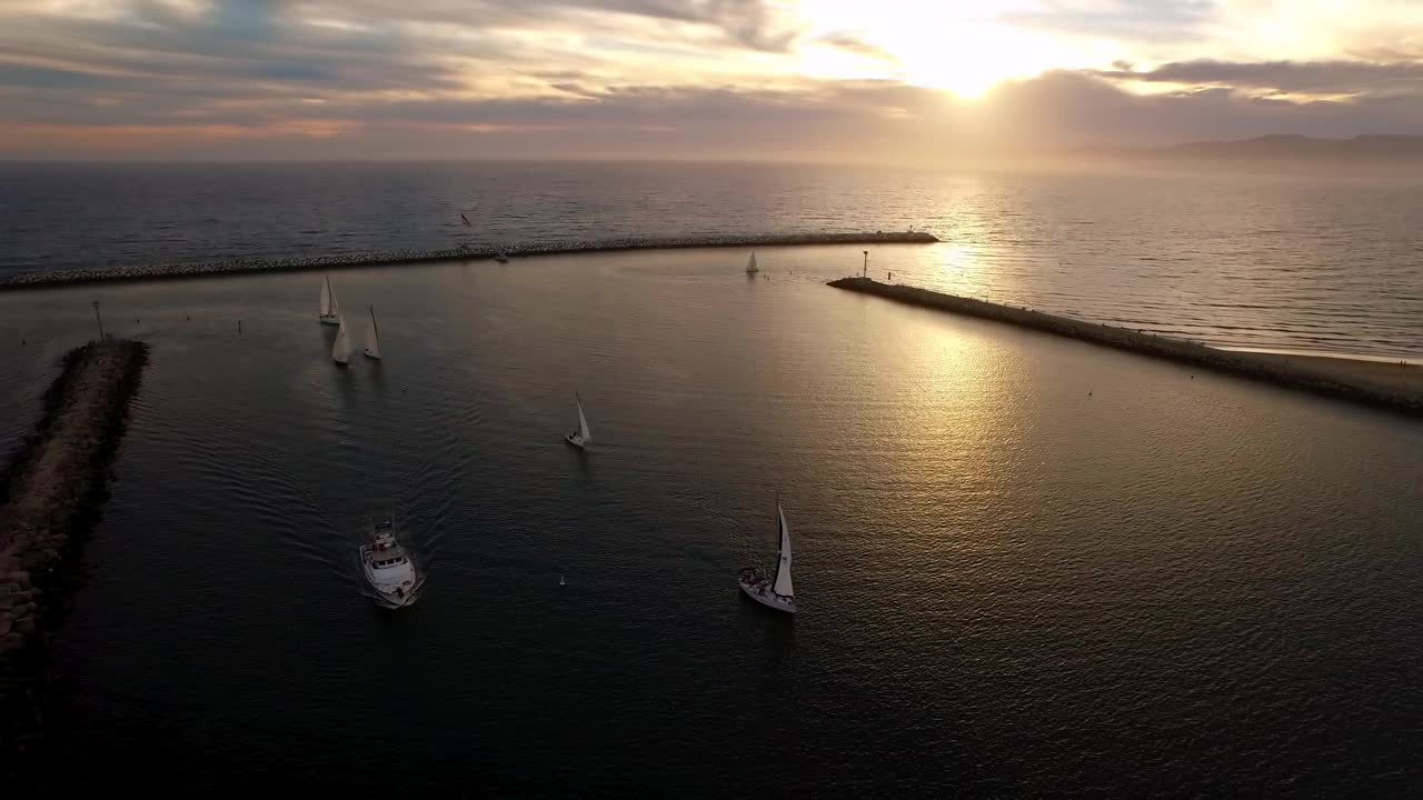 在日落期间，在荡漾的海洋中，游艇的空中倾斜向下风景视频素材