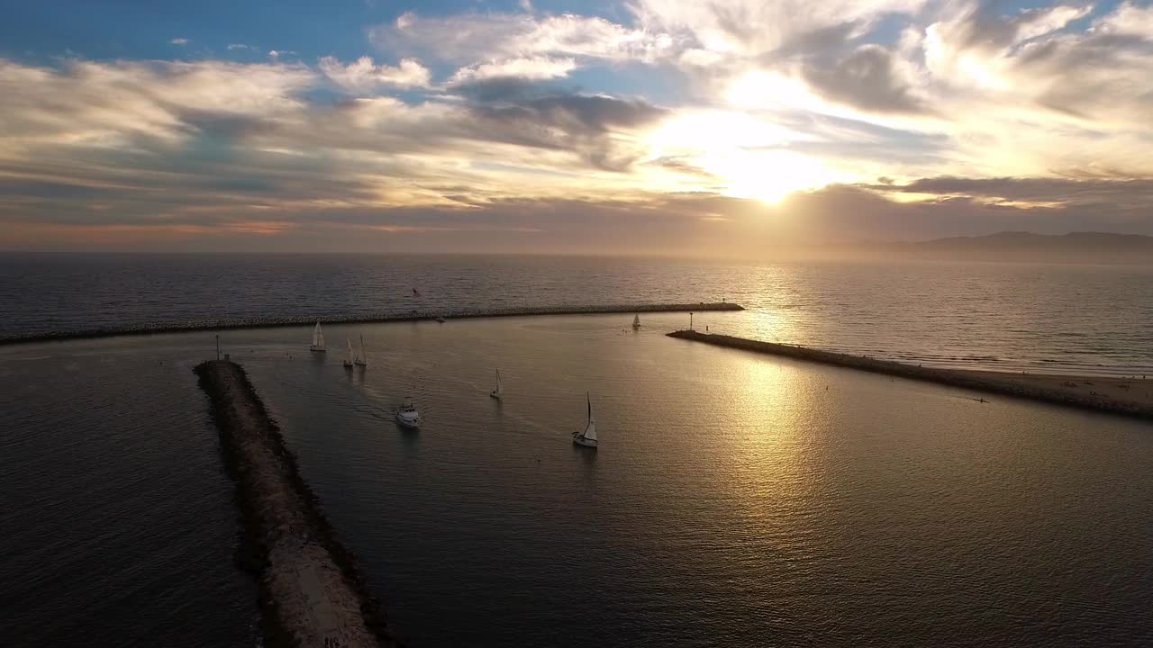 在宁静的日落期间，游艇在荡漾的大海中移动的空中景色-加州的雷伊码头视频素材