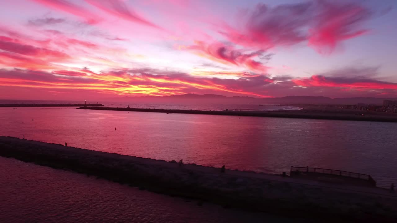 在日落时，在天空中戏剧性的云下，在荡漾的大海中航拍风景优美的码头-加利福尼亚州的雷伊码头视频素材