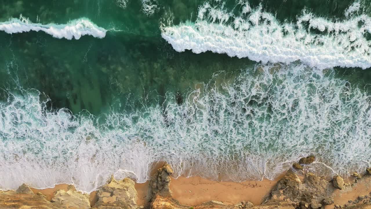 空中俯瞰的海洋冲浪和沙滩海岸与岩石。有泡沫的强大海浪视频素材