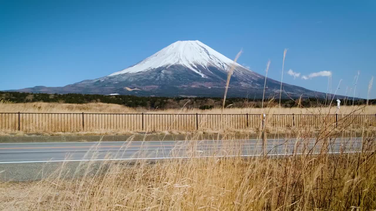 在蓝天的日子里，富士山映衬着群山和草地，是游客和旅行者的地标和目的地。大自然的美在平和中伴着缓慢的冬天的风视频素材