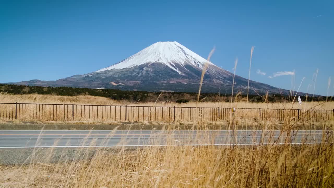 在蓝天的日子里，富士山映衬着群山和草地，是游客和旅行者的地标和目的地。大自然的美在平和中伴着缓慢的冬天的风视频下载