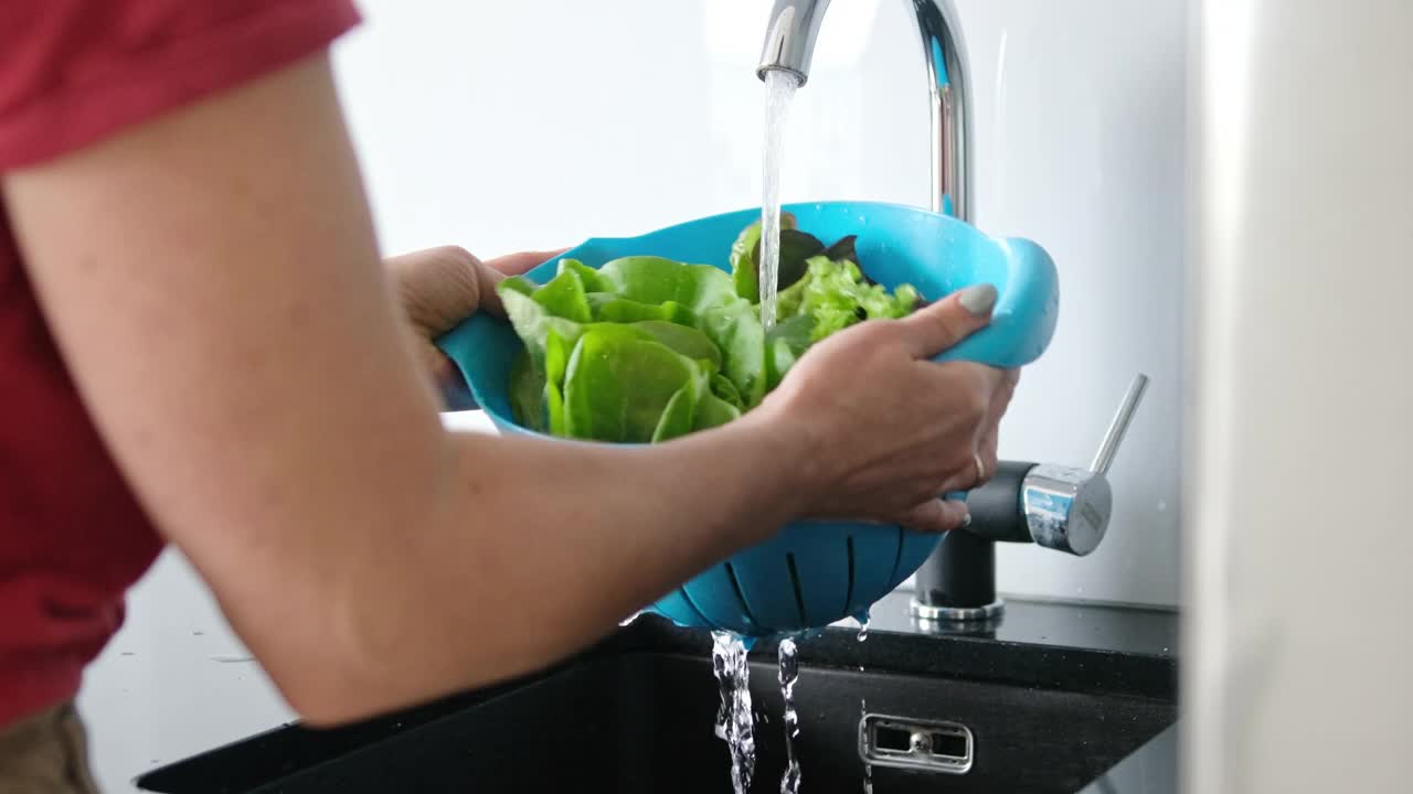 年轻女子在厨房洗生菜叶视频素材