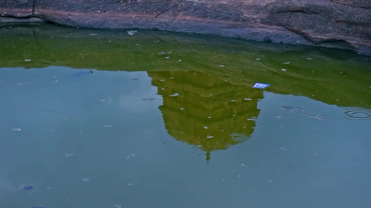 印度卡纳塔克邦巴达米的古代湿婆庙(湿婆庙上)，前景是水的倒影。视频下载