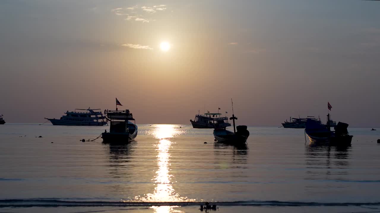 夕阳将泰国渔船沐浴在金色大海的剪影中，捕捉到一天的平静结束。视频素材