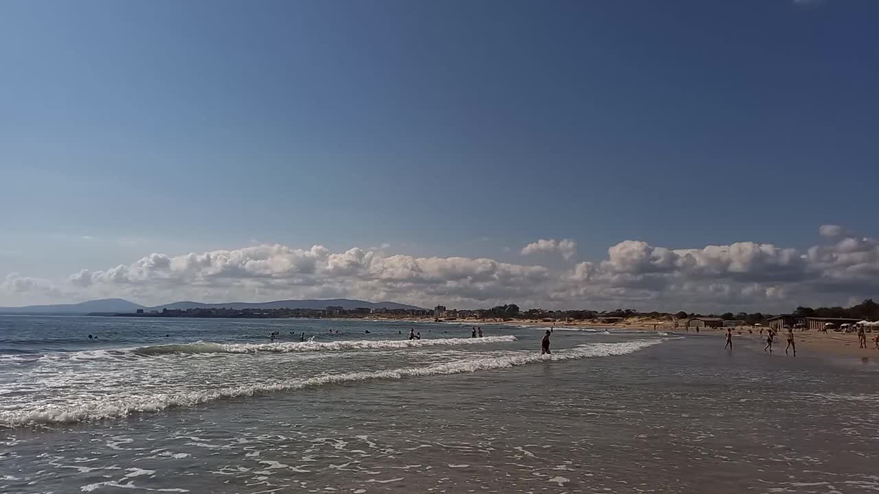 海景。在炎热的夏天，人们在海里放松和游泳。在保加利亚黑海沿岸度假。滨海的珍珠海滩视频下载