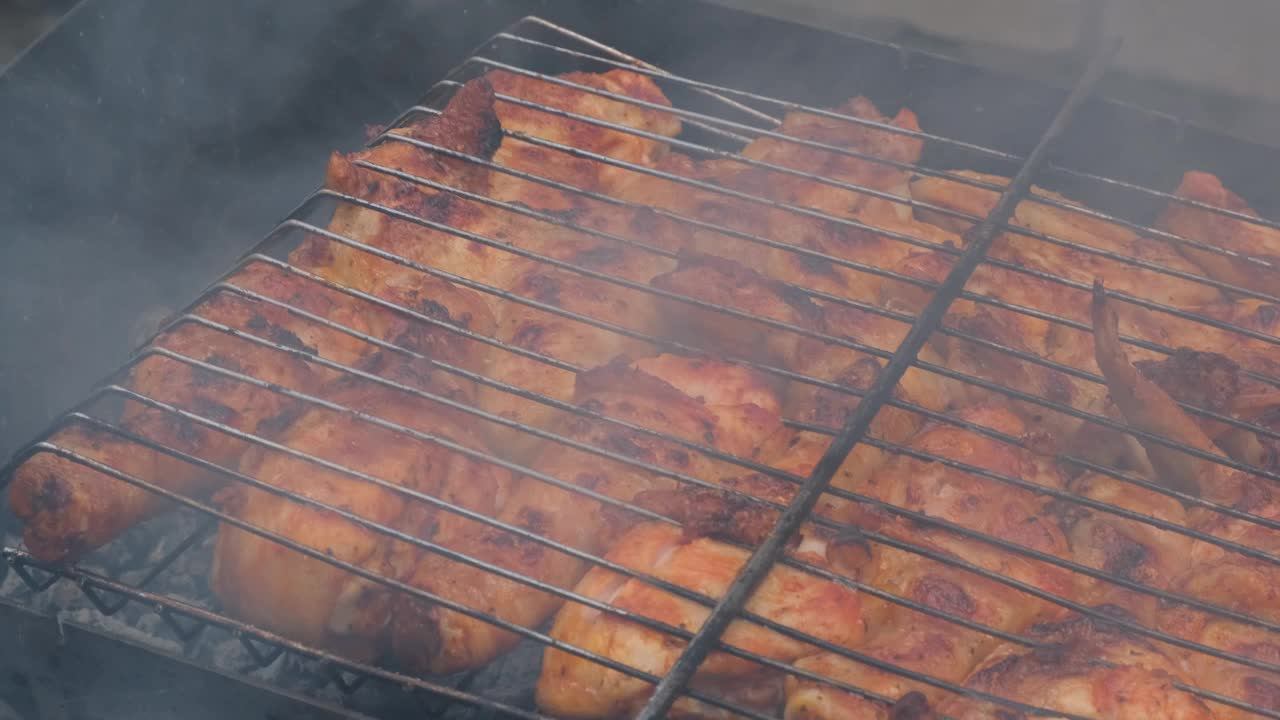 美味的鸡肉在户外烧烤架上煎炸。调味料落在新鲜的烤鸡翅上。夏日派对美食点子。多汁的烤鸡腿视频素材