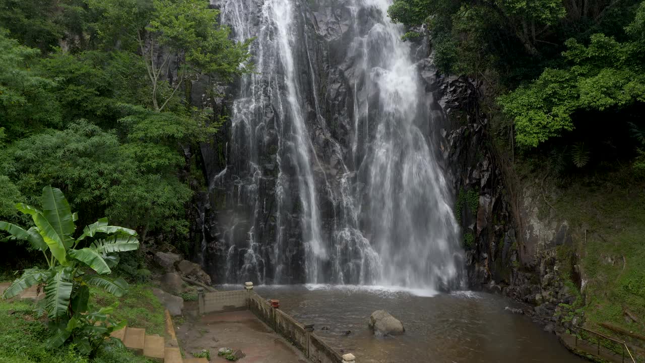 在多巴湖附近，郁郁葱葱的埃弗拉塔瀑布从岩石悬崖上倾泻而下，周围是绿色的树叶视频素材