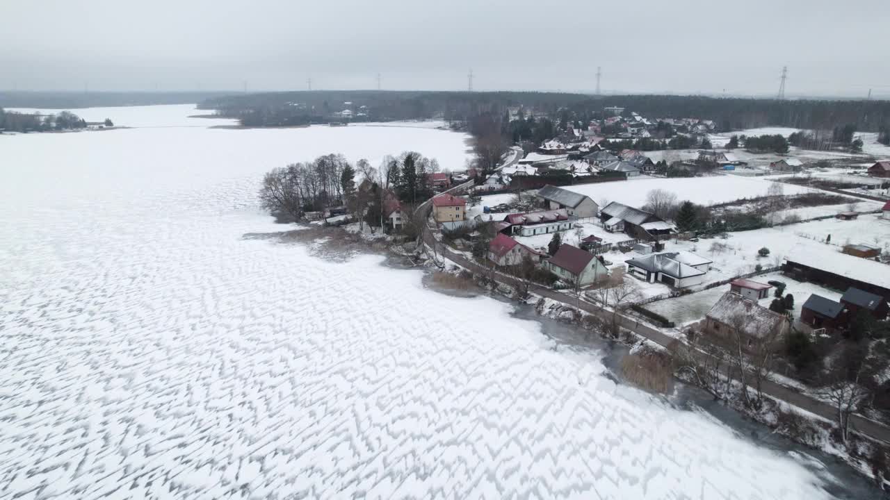 乡村波兰村庄在一个冰冻的湖在冬天，雪乡，航拍摄影车视频素材