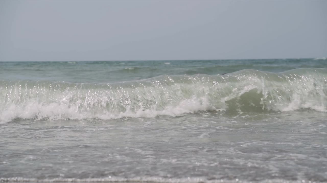 男子在海滩上的巨大海浪中游泳视频素材