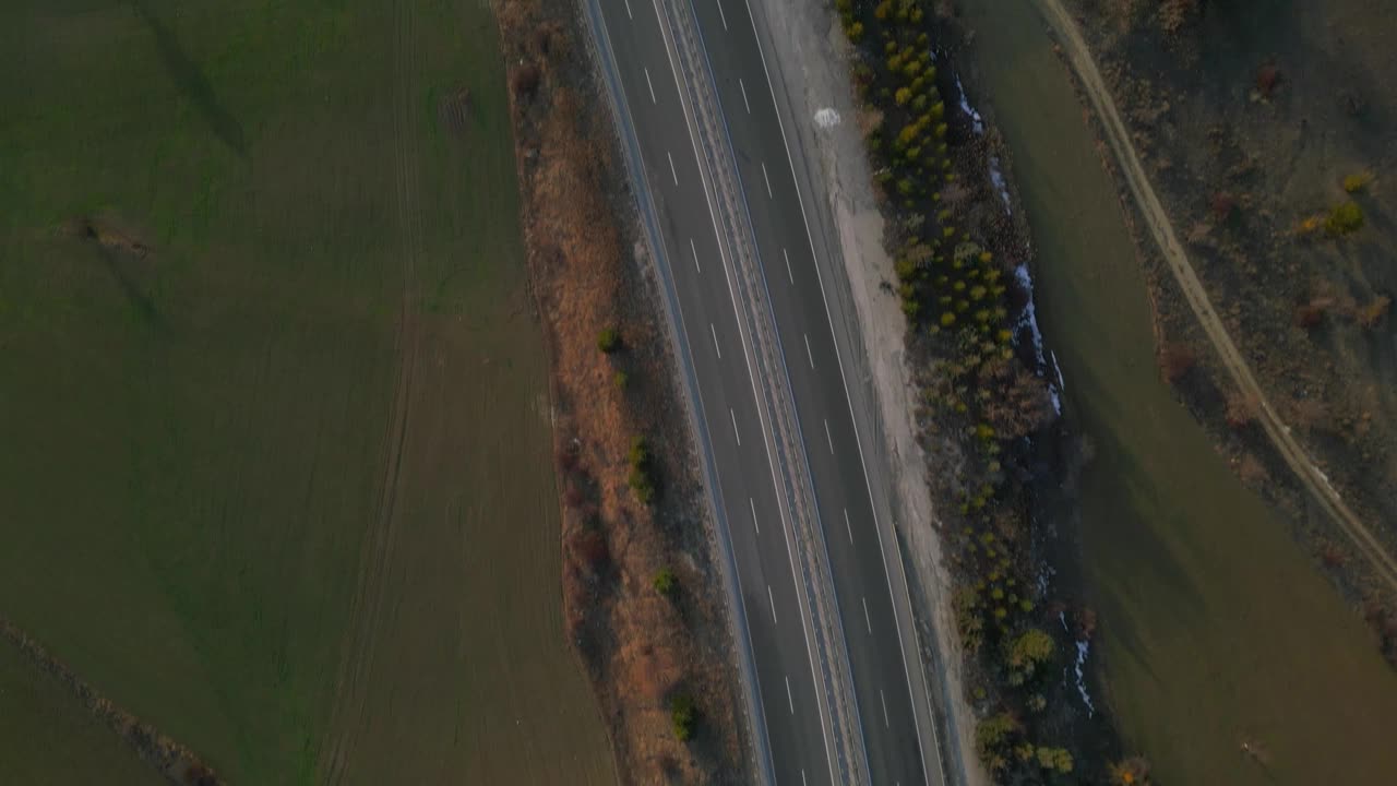 鸟瞰图，汽车行驶在两旁是建筑物和树木的沥青公路上视频素材