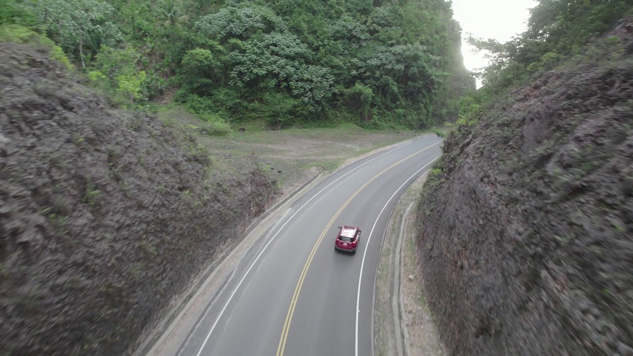 空中跟踪红色汽车行驶在切割山路，拉斯特伦纳斯，多米尼加共和国视频素材